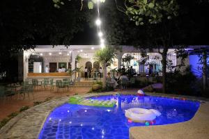 a swimming pool at night with a table and chairs at Mad Monkey Dumaguete in Dumaguete