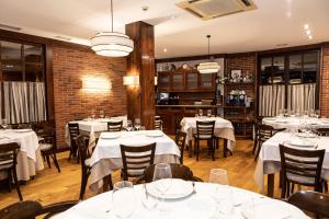 a restaurant with white tables and chairs and a brick wall at Hotel Restaurante De Torres in Felechosa