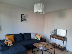 ein Wohnzimmer mit einem blauen Sofa und einem Tisch in der Unterkunft Stade de France 6 pers in Saint-Denis