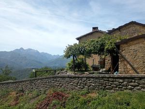 un mur en pierre à côté d'une maison avec des montagnes en arrière-plan dans l'établissement La casa del pozzo, à Sillico
