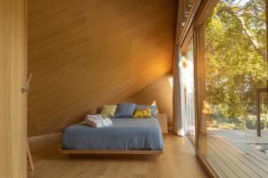 a bed in a room with a large window at Cabañas de Xarás, Mimosa in Marín