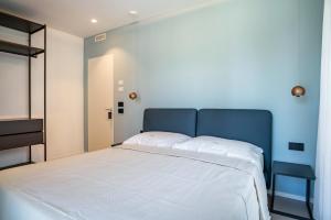 a bedroom with a large white bed and a blue wall at Appartamento Midum Garden Nord in Trento
