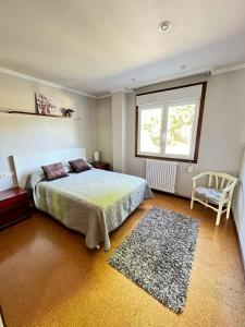 1 dormitorio con cama, ventana y silla en Casa Manola, en Teo