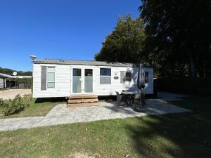 een witte trailer met een tafel en stoelen in een tuin bij Vakantiepark Klein Vink - 190 in Arcen