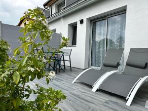 a patio with two chairs and a table on a building at La Villa Perchée, Appartements Élégants, sauna Privé, sport, terrasses et Vue Panoramique, Parking protégé, proche PARIS in Saint-Prix