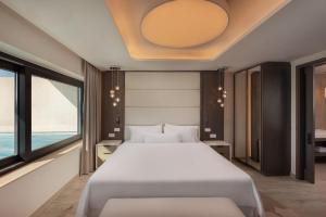 a bedroom with a large white bed and windows at The Westin Dragonara Resort, Malta in St. Julianʼs
