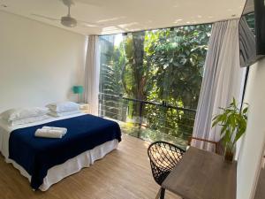 a bedroom with a bed and a large window at Pousada Armação de Camburi in Camburi