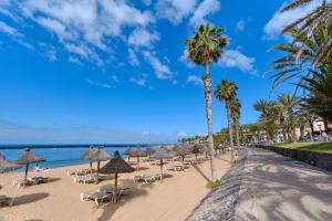 a beach with umbrellas and chairs and the ocean at Home2Book Modern Design Seaview Apt, Pool&Terrace in Playa de las Americas