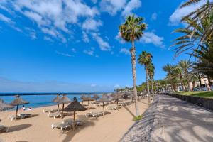 una playa con sombrillas y sillas y el océano en Home2Book Modern Design Seaview Apt, Pool&Terrace en Playa de las Américas