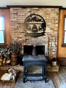 chimenea de ladrillo con estufa en la habitación en Hannah's Birch Farm 10 Min to Gore Ski Mt., en Johnsburg
