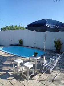 grupa krzeseł i parasol obok basenu w obiekcie Casa de praia em Carapibus w mieście Jacumã