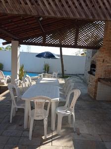 einen Tisch, Stühle und einen Regenschirm auf einer Terrasse in der Unterkunft Casa de praia em Carapibus in Jacumã