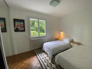 a bedroom with two beds and a window at Maison dans les bois avec piscine in Encausse-les-Thermes +29 photos