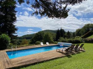 a swimming pool with chairs and a wooden deck at Maison dans les bois avec piscine in Encausse-les-Thermes