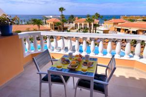 una mesa con un plato de comida en el balcón en Home2Book Modern Design Seaview Apt, Pool&Terrace en Playa de las Américas
