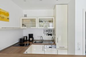 a kitchen with white cabinets and a sink at Besilima Apartments Deidesheim - zentral & ruhig am Kurpark in Deidesheim