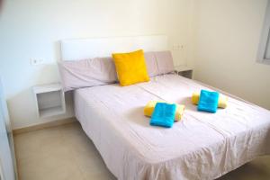 een wit bed met gele en blauwe kussens erop bij Oasis Holiday House in Orihuela