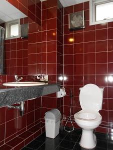 a red tiled bathroom with a toilet and a sink at B.S. Court Hotel Sathorn in Bangkok