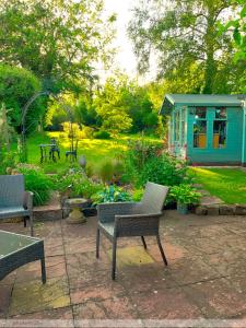 a patio with chairs and a garden with a blue house at Portland House in Whitchurch