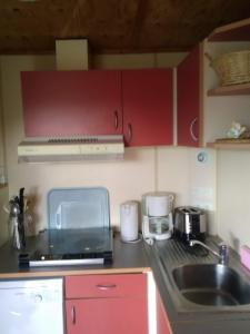 a small kitchen with red cabinets and a sink at la Frégière Chalets in Clairvaux-dʼAveyron