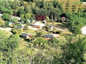 une vue aérienne sur une ferme avec des maisons et des arbres dans l'établissement la Frégière Chalets, à Clairvaux-dʼAveyron