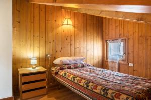 1 dormitorio con 1 cama en una pared de madera en Appartamento Cinzia, en Moena