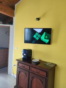 einen TV an einer gelben Wand mit einem Holzschrank in der Unterkunft Assisi il Panorama in Petrignano