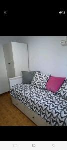 - un lit avec une couette en noir et blanc et un oreiller rose dans l'établissement Apartamento playa, à Laredo