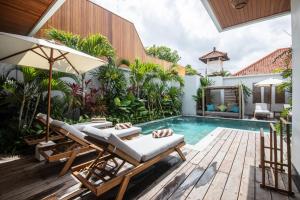 an outdoor swimming pool with a lounging chair and a lounging area at Zayana Villas Resort Seminyak in Seminyak