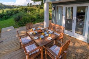 a wooden table with four chairs on a deck at Trewhiddle Villa 07 in St Austell