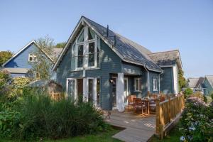 a blue house with a wooden deck with a table at Luxurious 3 Bedroom New England Style Villa - Trewhiddle V7 in St Austell