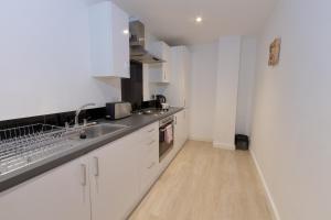 a kitchen with white cabinets and a wooden floor at Cosy Studio Apt in Preston near City Centre in Preston