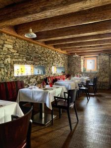 a dining room with tables and chairs and a stone wall at Hotel Friedheim in Weggis