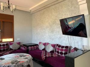 sala de estar con sofá y TV de pantalla plana en villa avec piscine à louer, en Bir Jedíd Saint-Hubert