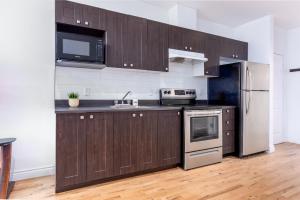 een keuken met houten kasten en een roestvrijstalen koelkast bij AAA Location - Bright and Cozy Apartment in Montreal