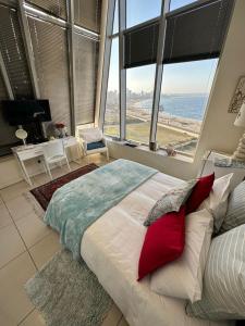 1 cama grande con almohadas rojas en una habitación con ventanas grandes. en DNA Dream Home, en Durban