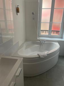 baño con bañera blanca y ventana en Hôtel & Restaurant Le Patio VICHY, en Vichy