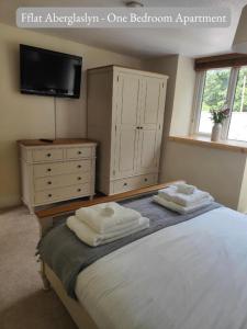 a bedroom with a bed with a dresser and a tv at Llew Accommodation - The Townhouse in Beddgelert