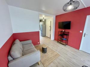 - un salon avec un canapé et un mur rouge dans l'établissement Appartement 3 chambres - Proche Dock 76 - 128, à Rouen