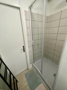 La salle de bains est pourvue d'une douche avec une porte en verre. dans l'établissement Appartement 3 chambres - Proche Dock 76 - 128, à Rouen