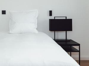 een slaapkamer met een wit bed en een zwart nachtkastje bij CH Longstay 33 in Kortrijk
