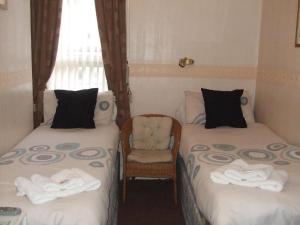 Habitación con 2 camas individuales y silla en Fern Villa Hotel - Albert Road, en Blackpool
