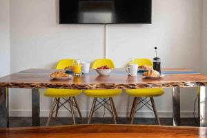 uma mesa de madeira com cadeiras amarelas e comida em Kingsgate Bay Bungalow - 950meter to Beach Dog friendly em Kent