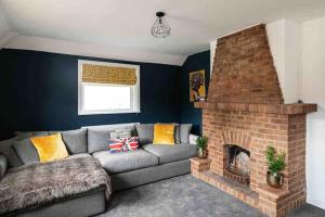 a living room with a couch and a brick fireplace at Kingsgate Bay Bungalow - 950meter to Beach Dog friendly in Kent