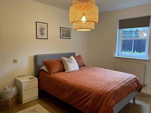 a bedroom with a bed with a orange comforter and a window at The Quorndon in Kegworth