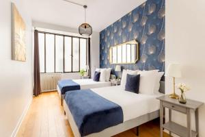 duas camas num quarto com azul e branco em Cosy 2 bedrooms apartment - Louvre Museum em Paris