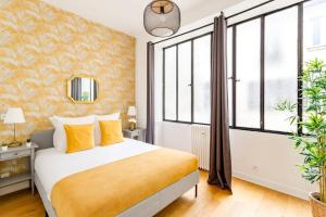 um quarto com uma cama com lençóis amarelos e janelas em Cosy 2 bedrooms apartment - Louvre Museum em Paris