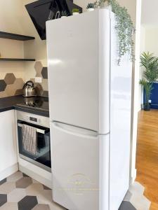 een witte koelkast in een keuken naast een fornuis bij Le Bleu Colbert in Versailles