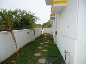 an empty alley with a white wall and grass at ECR Holiday in Chennai