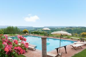 a swimming pool with tables and umbrellas and pink flowers at Fattoria la Gigliola - Il Frantoio in Montespertoli